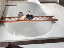 Baignoire rectangulaire en acier émaillé, blanc brillant, avec tablette en bois et accessoires de salle de bain, dans une salle de bain moderne.